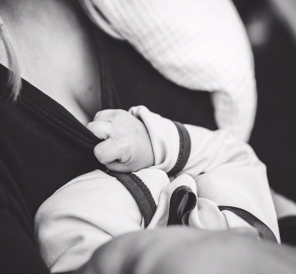 baby tugging at mother's shirt